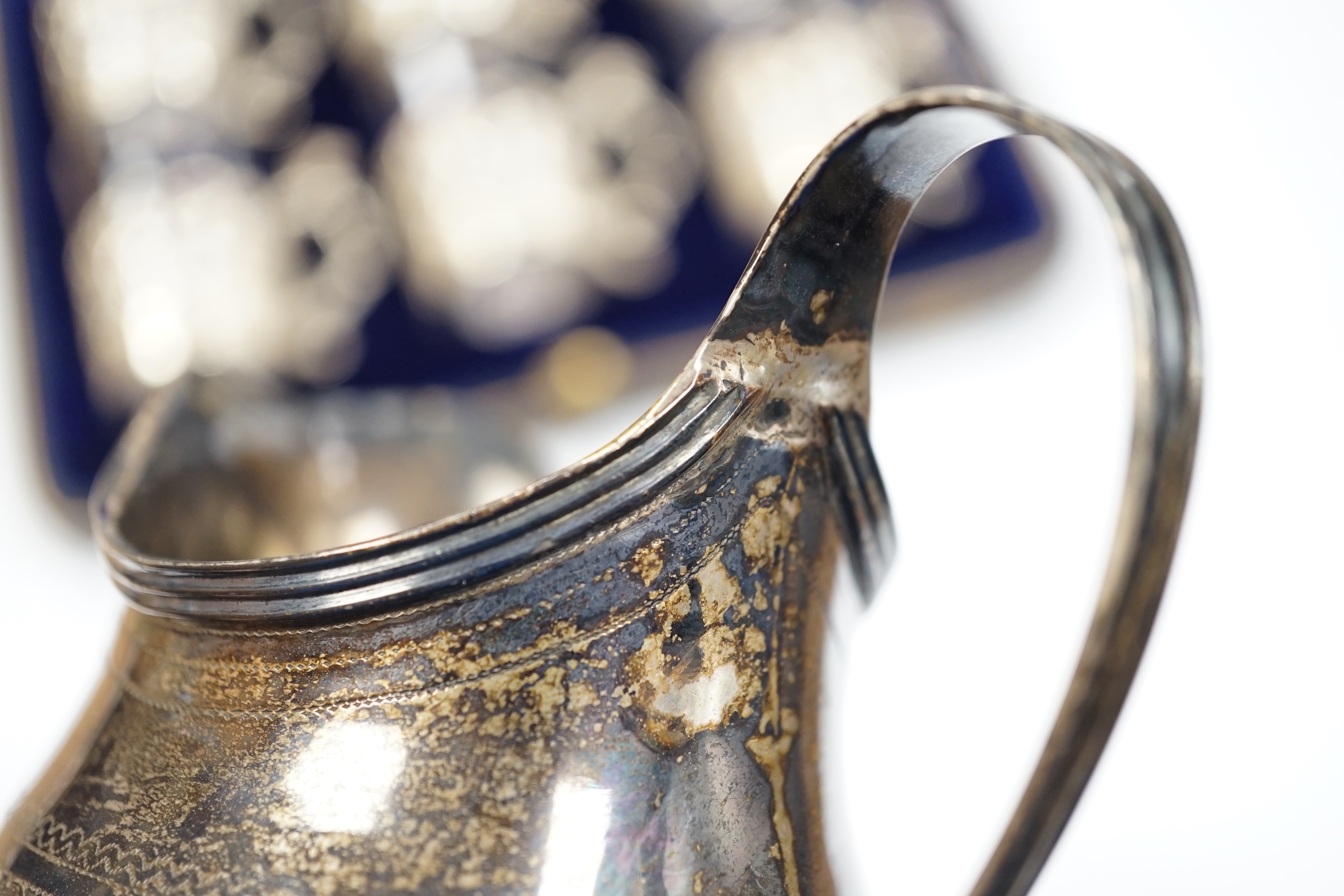 A George III engraved silver helmet shaped cream jug, Francis Purton?, London, circa 1790, height 10.6cm (a.f.), together with a cased set of six George V silver coffee can holders, with glass inserts, Marples & Co, Birm